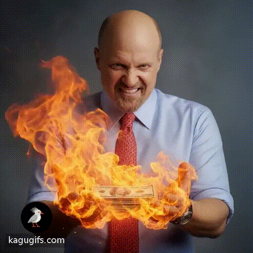 Bald man with goatee in light blue shirt and red tie lit a stack of money on fire, flames rising from his hands with an intense expression.