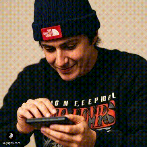 Harry wearing a navy beanie and graphic tee, leaning forward with focused expression while operating a calculator in his hands.