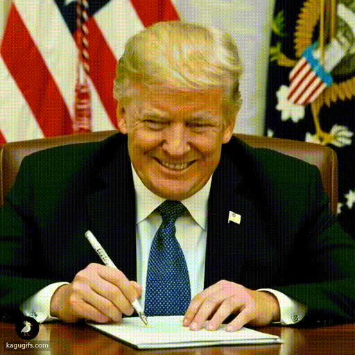 A man with distinctive blonde swept-back hair, wearing a dark navy suit with a blue polka-dot tie and American flag pin, smoking a joint while leaning over a desk signing a document with focused expression.