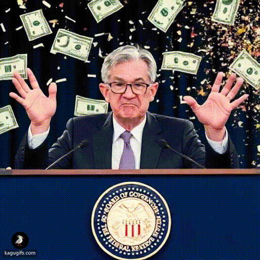 Jerome Powell with gray hair and glasses wearing a dark suit and purple tie, smiling broadly while throwing dollar bills in the air with both hands raised in a celebratory gesture at a festive party.