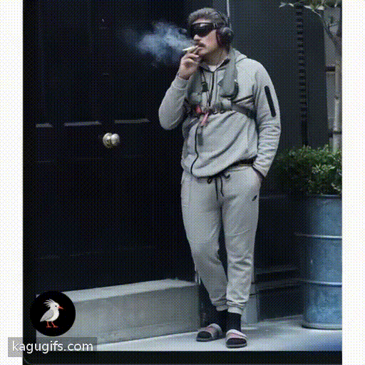 Man in gray tracksuit with dark mustache and aviator blindfold puffing a cigarette, wearing black headphones and slides, casual stance with relaxed posture, subtly shifting weight and exhaling smoke.